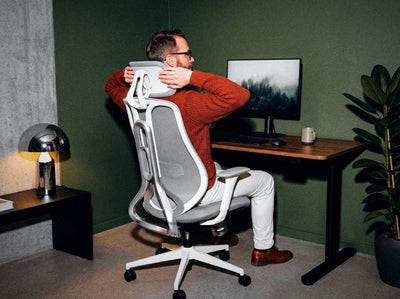 Mees seab Ergonix OmniSit Pro toolis istudes peatuge, vaade tagant
